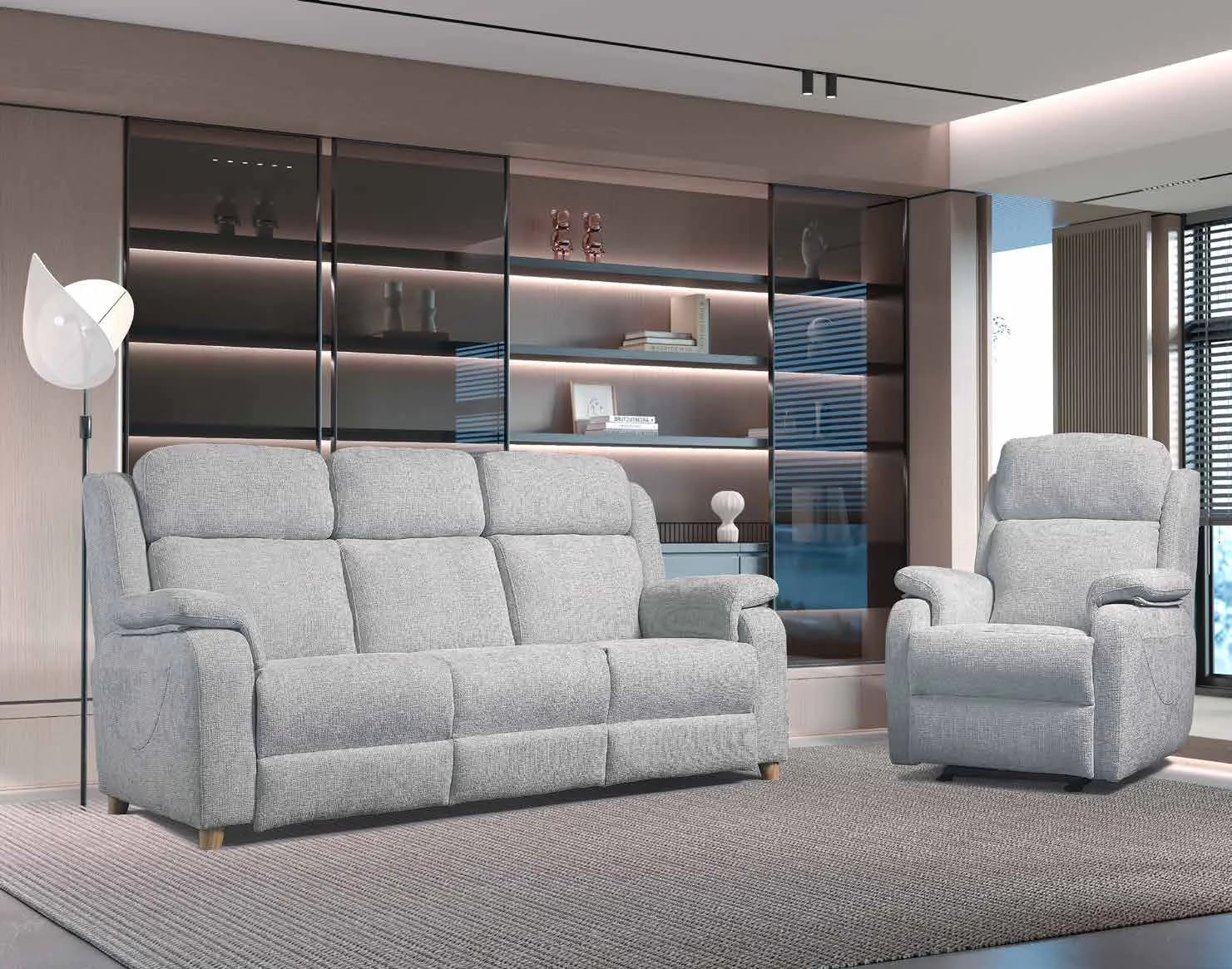 Sofá de tres plazas y butaca relax de Tapridel en un salón con librería iluminada